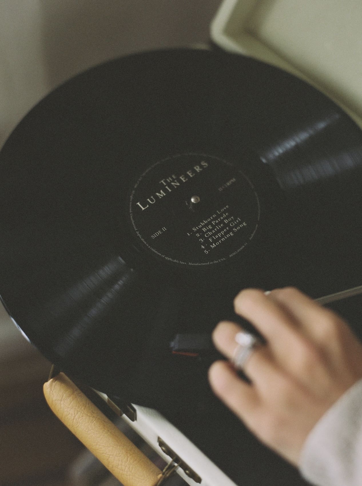 Hand placing vinyl record on vintage record player for music.