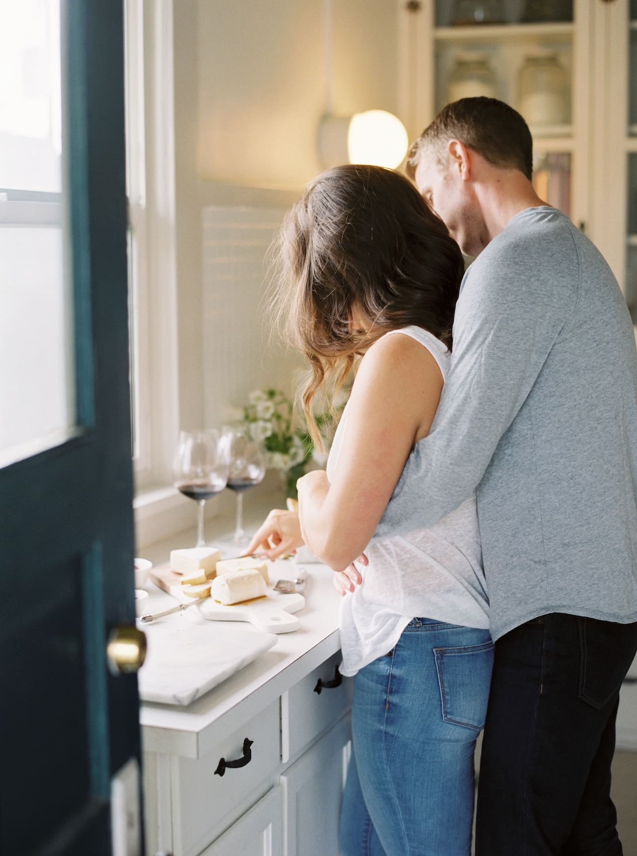 Couple preparing cheese and wine in a cozy kitchen setting