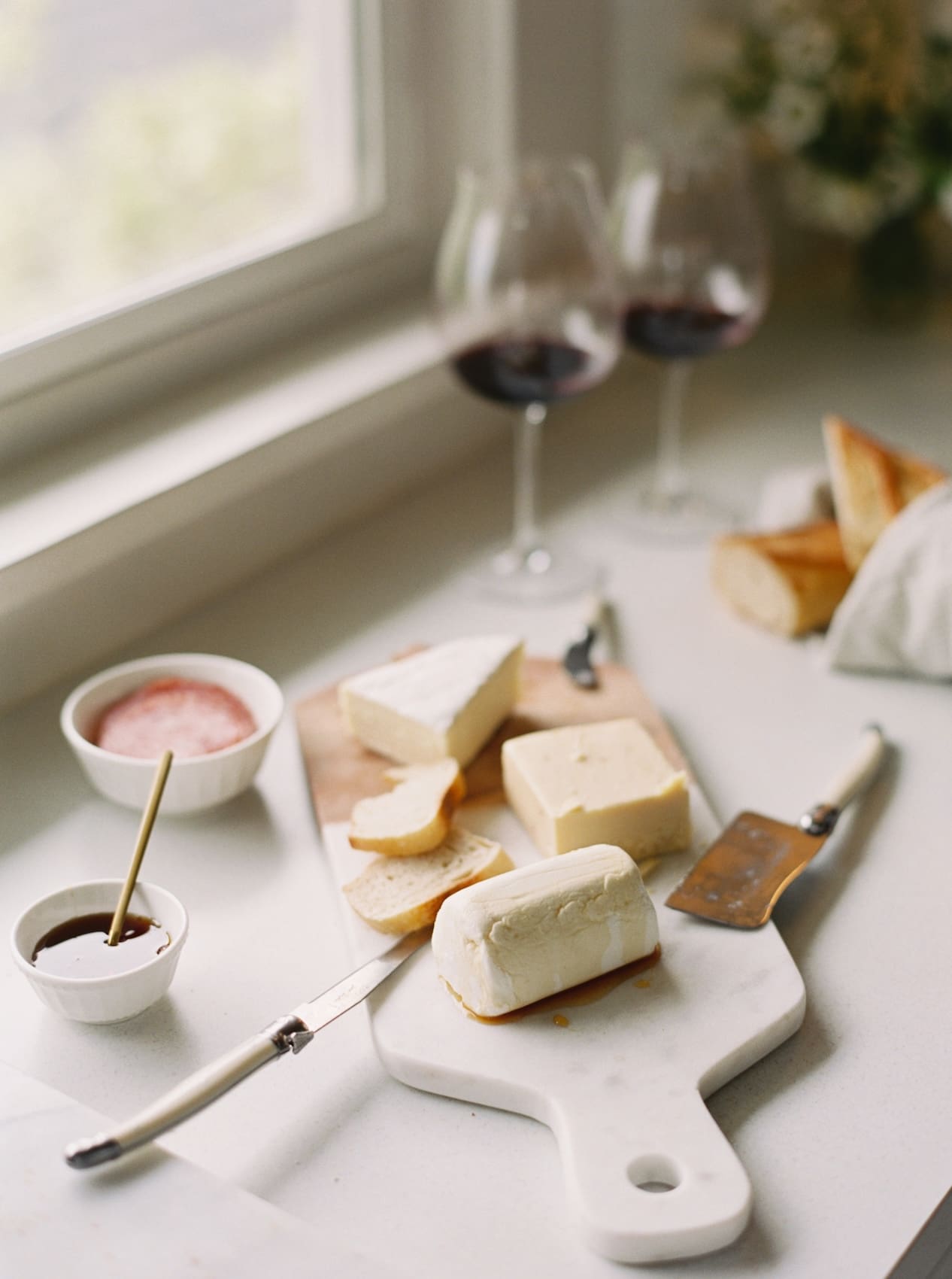 Elegant cheese and wine setup on a bright white kitchen table