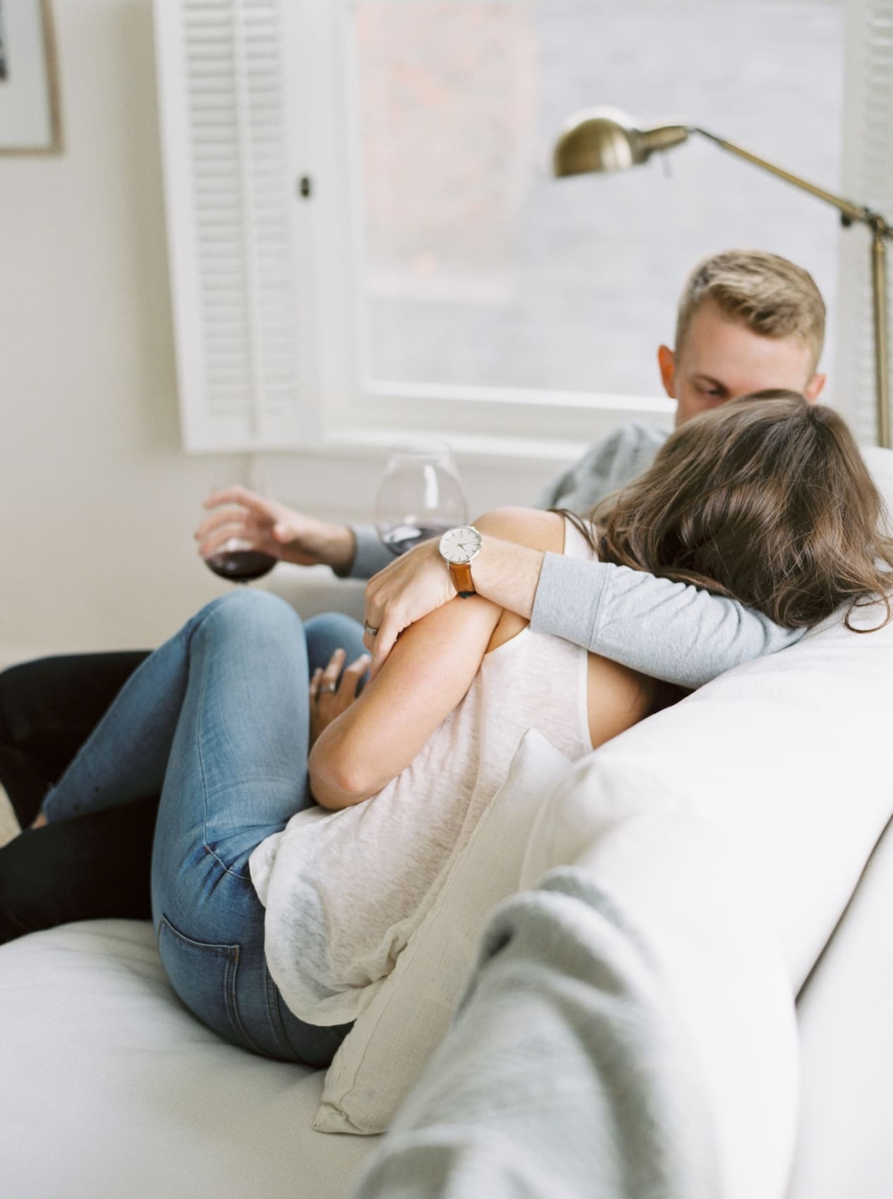 Couple cuddling on a cozy couch enjoying wine at home
