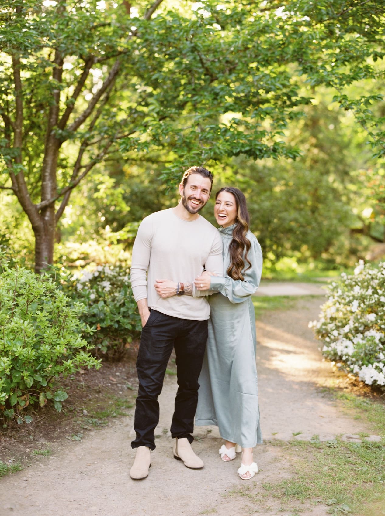 Couple smiling together in a lush green garden pathway