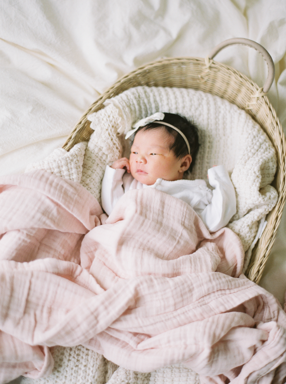 asian baby girl newborn laying in basket with pink blanket