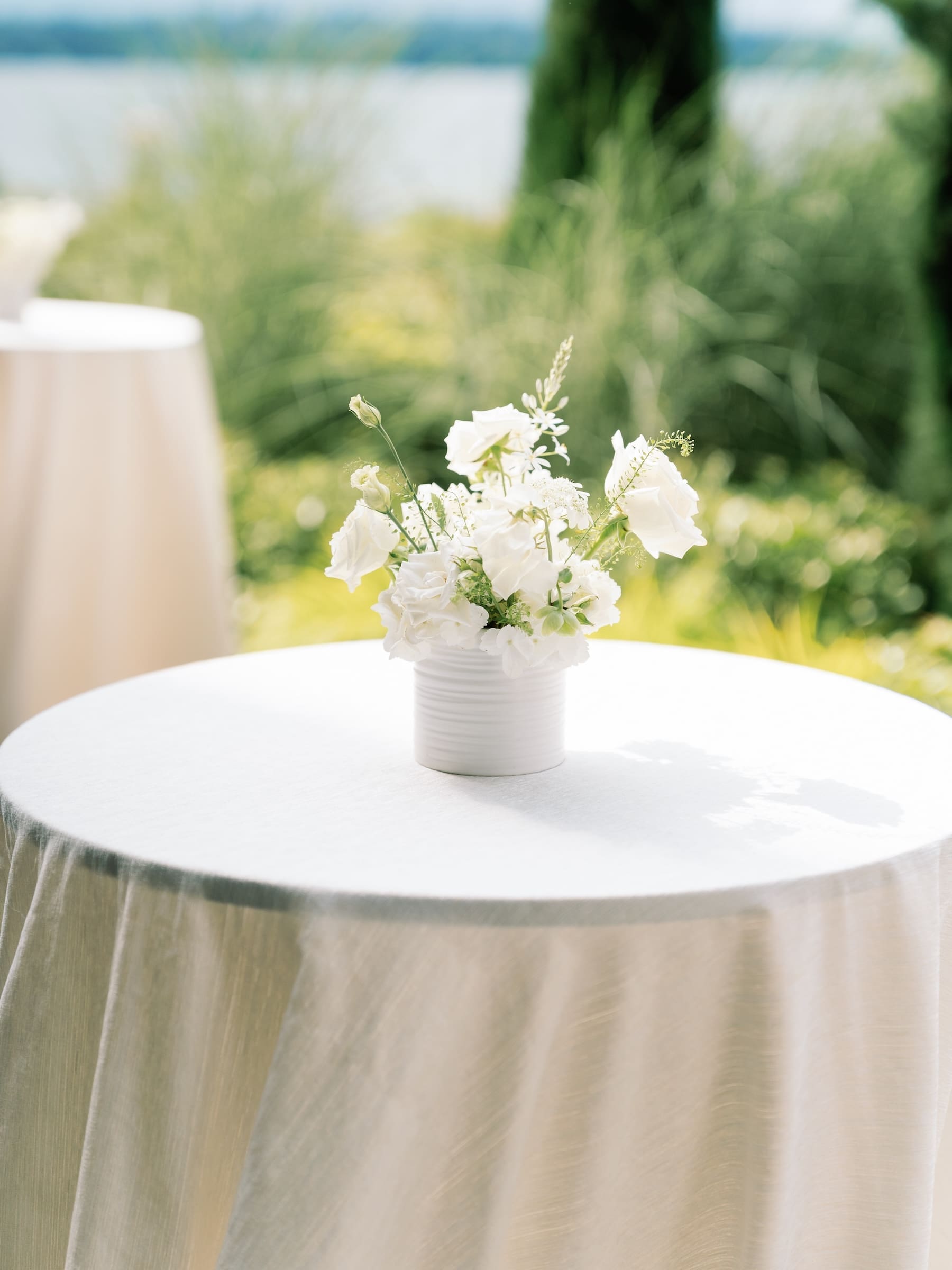 White floral centerpiece on an outdoor table in sunlight