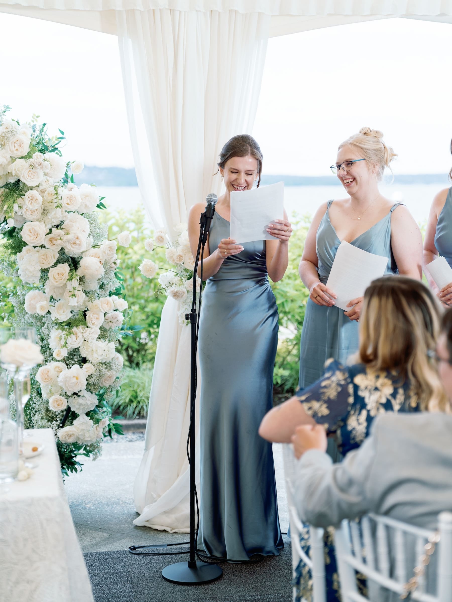 Bridesmaids smiling during wedding ceremony speech outdoors