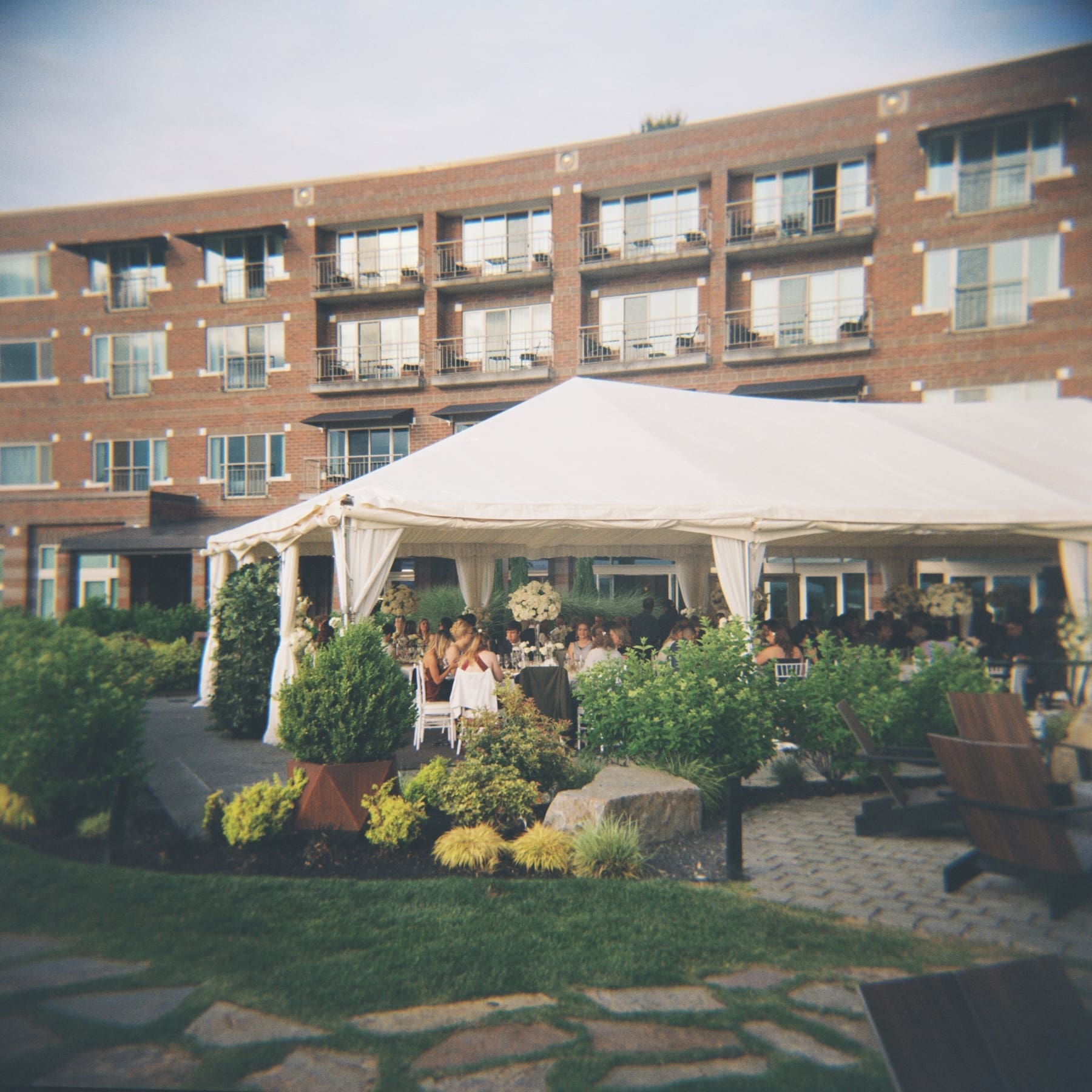 Outdoor wedding under a white canopy near a brick building