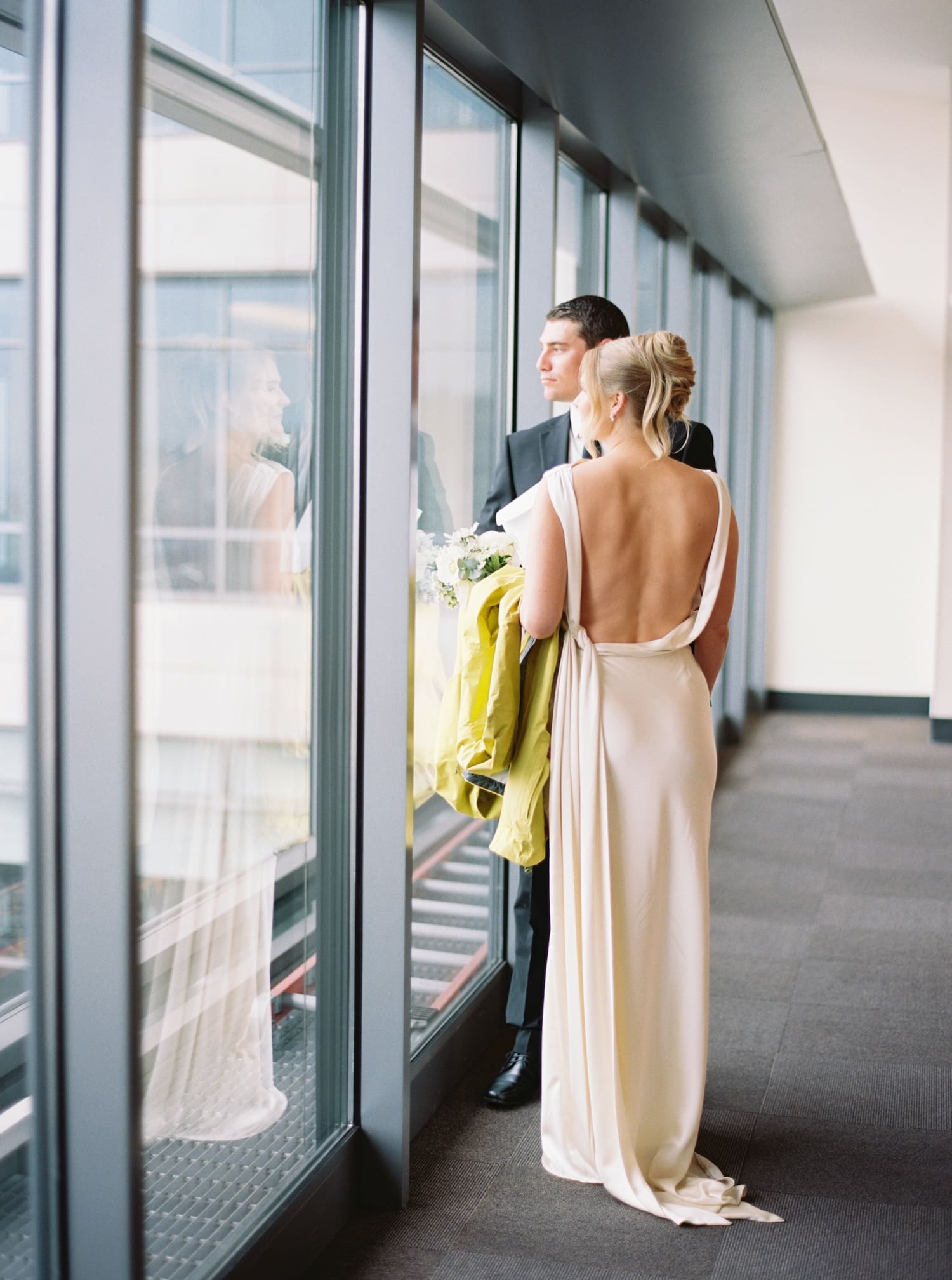 Bride and groom look out window at Seattle Courthouse waiting for Elopement